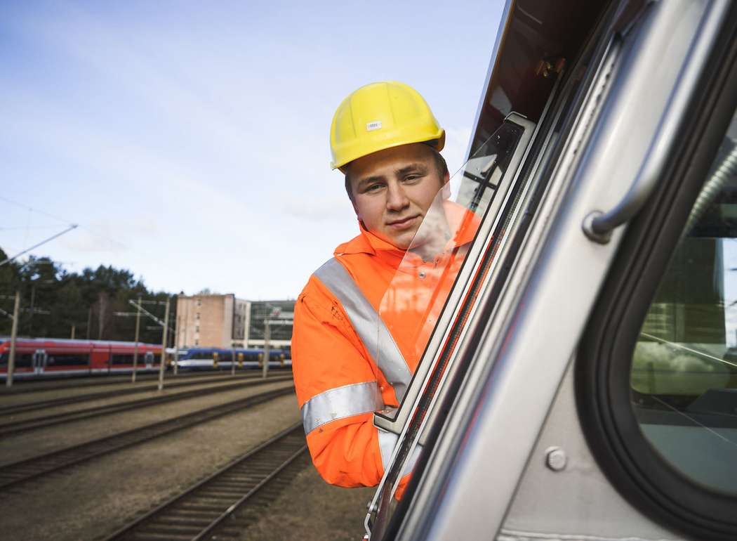 Junger Auszubildender Eisenbahner im Betriebsdienst sieht aus dem Fenster im Führerstand